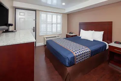a hotel room with a bed and a flat screen tv at Travelodge by Wyndham Harbor City in Harbor City