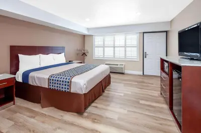 a hotel room with a bed and a flat screen tv at Travelodge by Wyndham Harbor City in Harbor City