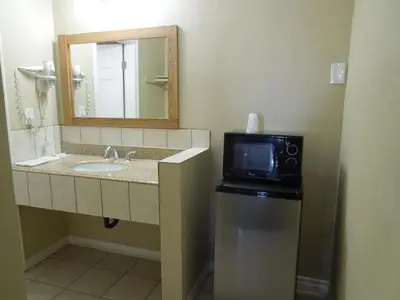 a bathroom with a sink and a mirror and a microwave at Castaway Motel in Orange