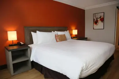 a bedroom with a large white bed with two lamps at Lincoln Hotel Monterey Park Los Angeles in Monterey Park