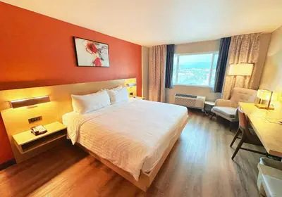 a hotel room with a large bed and a chair at Lincoln Hotel Monterey Park Los Angeles in Monterey Park