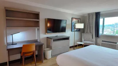 a hotel room with a bed and a desk and a television at Lincoln Hotel Monterey Park Los Angeles in Monterey Park
