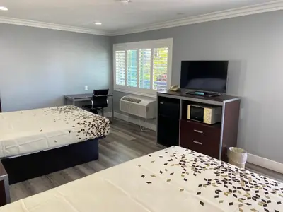 a hotel room with two beds and a flat screen tv at Regency Motel in Brea