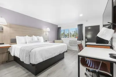 a hotel room with a bed and a desk at Inland Inn & Suites in San Bernardino