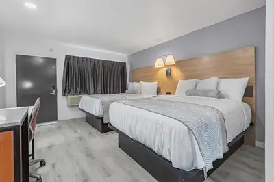 a hotel room with two beds and a desk at Inland Inn & Suites in San Bernardino