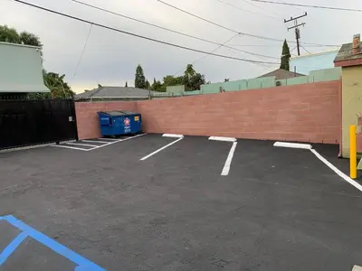 a parking lot next to a brick wall at Vegas motel in West Athens