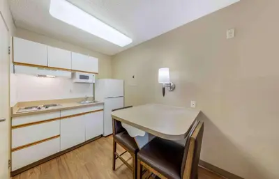 a small kitchen with a table and a refrigerator at Extended Stay America Suites - Los Angeles - LAX Airport - El Segundo in El Segundo