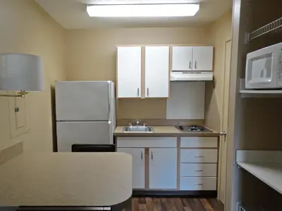 a small kitchen with white cabinets and a refrigerator at Extended Stay America Suites - Los Angeles - LAX Airport - El Segundo in El Segundo
