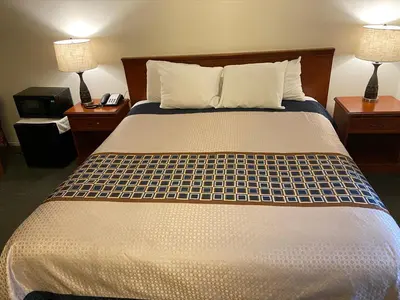a bed in a hotel room with two lamps and a phone at Vantage Point Inn - Woodland Hills in Woodland Hills