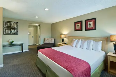 a hotel room with a large bed and a chair at Oxnard Inn Lancaster in Lancaster