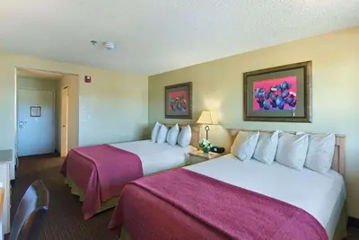 a hotel room with two beds with pink sheets at Oxnard Inn Lancaster in Lancaster