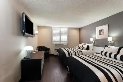 a hotel room with two beds and a flat screen tv at Ramada Plaza by Wyndham West Hollywood Hotel & Suites in Los Angeles