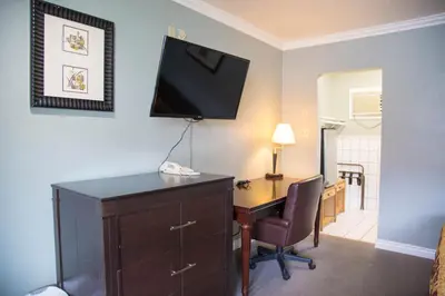a room with a desk and a television on a wall at Sahara Motel in Anaheim