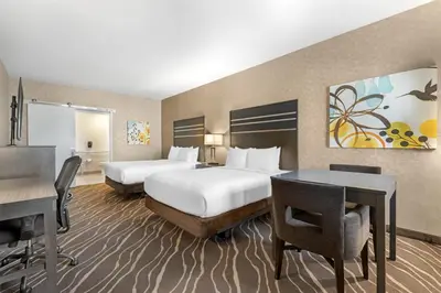 a hotel room with two beds and a desk at Best Western Plus Park Place Inn - Mini Suites in Anaheim