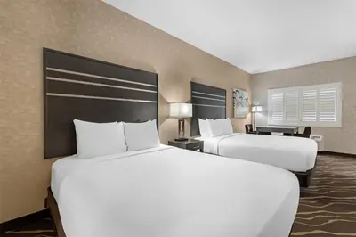 two beds in a hotel room with two bedsskirts at Best Western Plus Park Place Inn - Mini Suites in Anaheim