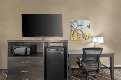 a room with a desk with a television and a chair at Best Western Plus Park Place Inn - Mini Suites in Anaheim