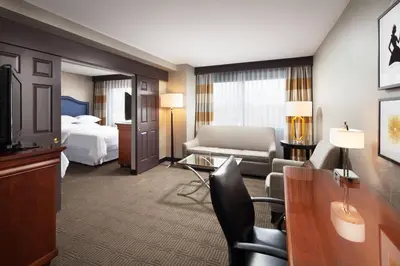 a hotel room with a bed and a living room at Sheraton Fairplex Suites & Conference Center in Pomona