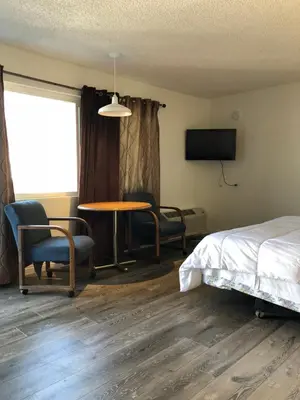 a room with a bed and a table and chairs at King Lodge Motel in Monterey Park