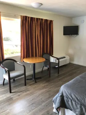 a room with a table and a chair and a bed at King Lodge Motel in Monterey Park