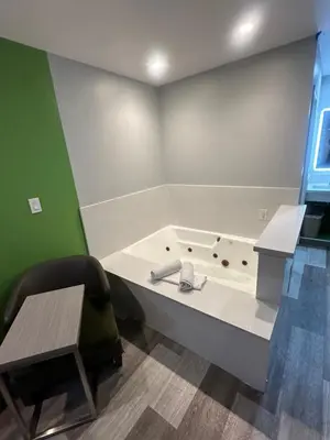 a room with a bath tub with a desk and a chair at Garden Inn San Gabriel in San Gabriel