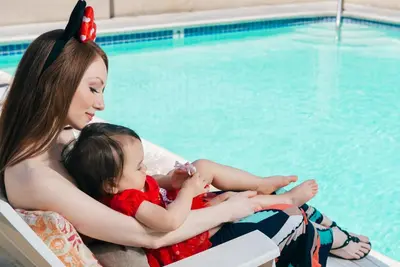 a woman and a child sitting next to a swimming pool at Alpine Inn near Convention Center and the Park in Anaheim
