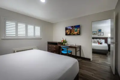 a bedroom with a bed and a desk with a mirror at Alpine Inn near Convention Center and the Park in Anaheim