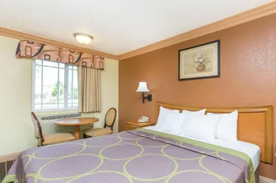 a hotel room with a bed and a table and a window at Super 8 by Wyndham Azusa in Azusa