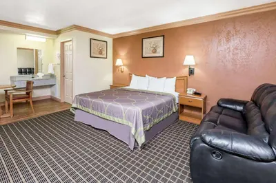 a hotel room with a bed and a couch at Super 8 by Wyndham Azusa in Azusa
