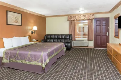 a hotel room with a bed and a chair at Super 8 by Wyndham Azusa in Azusa