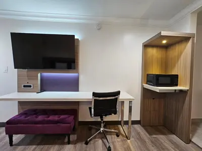 a room with a desk with a purple chair and a tv at Travelodge Inn & Suites by Wyndham Fullerton in Fullerton
