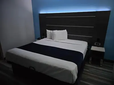 a bedroom with a large bed with a black headboard at Travelodge Inn & Suites by Wyndham Fullerton in Fullerton