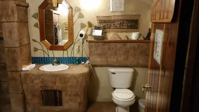 a bathroom with a toilet and a sink and a mirror at Castle Wood Theme Cottages- COUPLES ONLY in Big Bear Lake