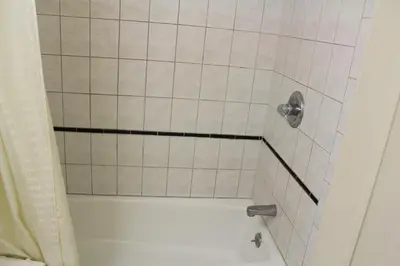 a bathroom with a shower with a white tile floor at Best Whittier Inn in Whittier
