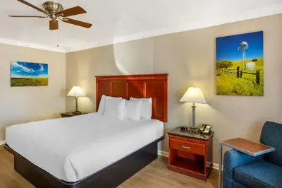 a hotel room with a bed and a blue chair at Best Western Heritage Inn in Bakersfield