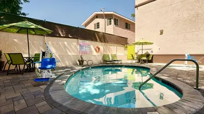 a swimming pool with chairs and umbrellas next to a building at Best Western Plus Glendale in Glendale