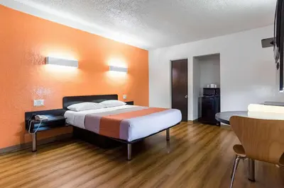 a hotel room with a bed with an orange wall at Motel 6-Long Beach, CA - International City in Long Beach