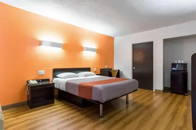 a bedroom with a bed with orange walls and wooden floors at Motel 6-Long Beach, CA - International City in Long Beach