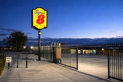 a store sign on a sidewalk next to a fence at Super 8 by Wyndham Bakersfield CA in Bakersfield