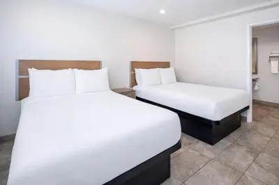 two beds in a hotel room with white sheets at Super 8 by Wyndham Bakersfield CA in Bakersfield