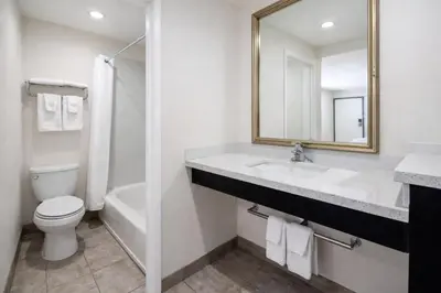 a bathroom with a sink and a toilet and a mirror at Super 8 by Wyndham Bakersfield CA in Bakersfield