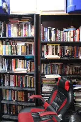 a red chair in front of a library filled with books at Artist Housing - Downtown in Los Angeles