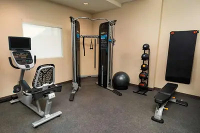 a room with a gym with exercise equipment and a monitor at Home2 Suites Bakersfield in Bakersfield