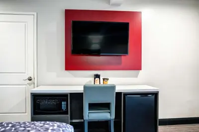 a desk with a chair and a tv on a wall at Rodeway Inn South Gate - Los Angeles South in South Gate