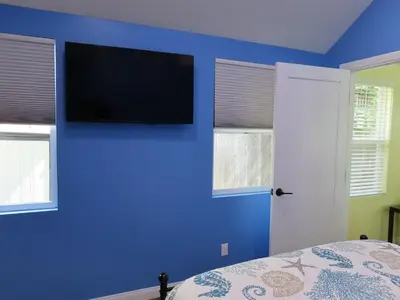 a bedroom with a blue wall with a flat screen tv at Hill Street Cottage in Los Angeles