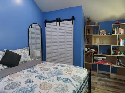 a bedroom with blue walls and a bed and a book shelf at Hill Street Cottage in Los Angeles