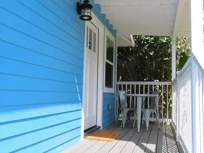 a blue house with a white door and a chair on the porch at Hill Street Cottage in Los Angeles