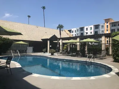 a swimming pool with chairs and umbrellas next to a building at Mikado Hotel in North Hollywood