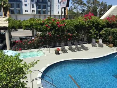 a swimming pool with chairs and flowers and a building at Mikado Hotel in North Hollywood