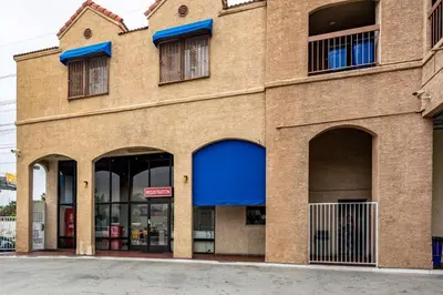 a brown brick building with blue awnings and windows at Motel 6-Gardena, CA - South in Gardena