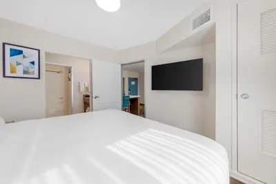 a white bedroom with a bed and a flat screen tv at Executive Residency by Best Western Victorville in Victorville